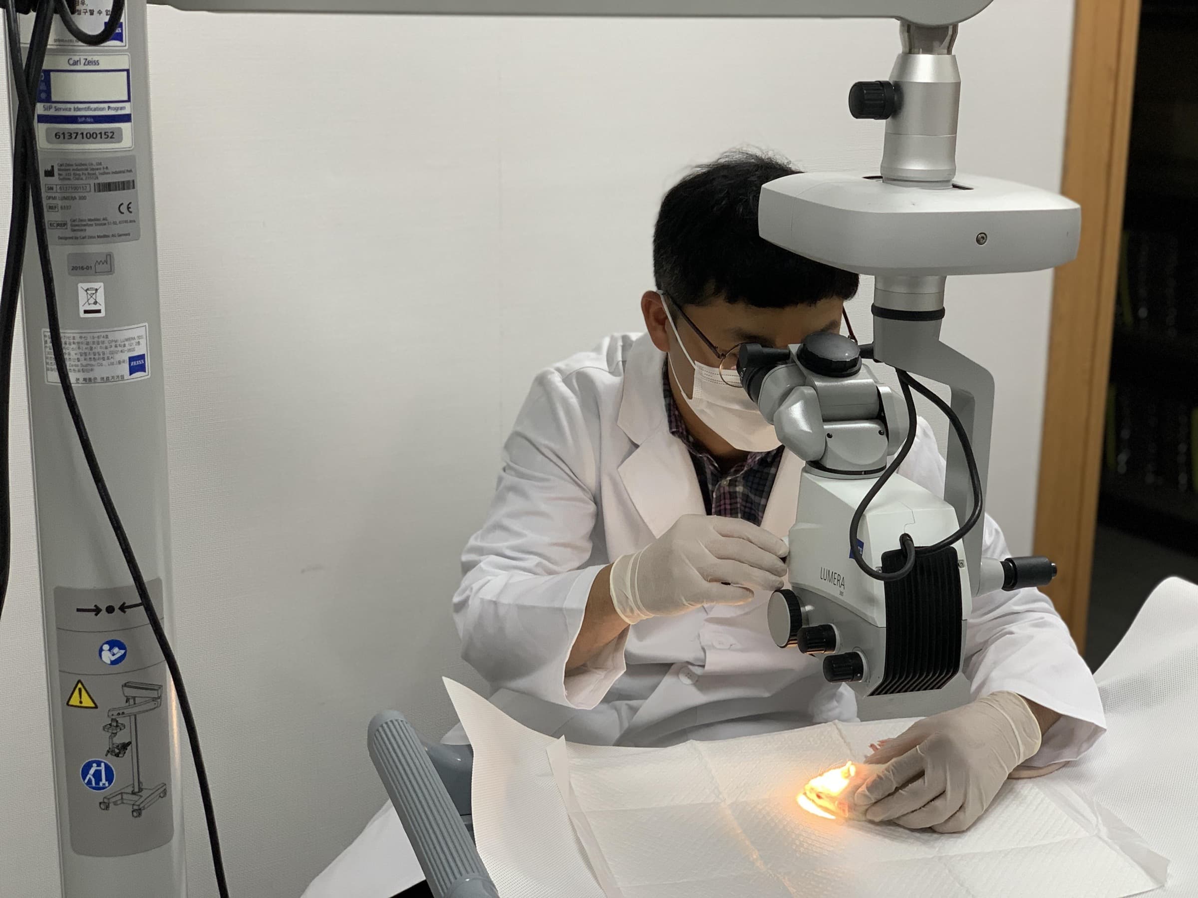 RudaCure researcher examining a cornea under an ophthalmic surgical microscope at the Central Research Institute